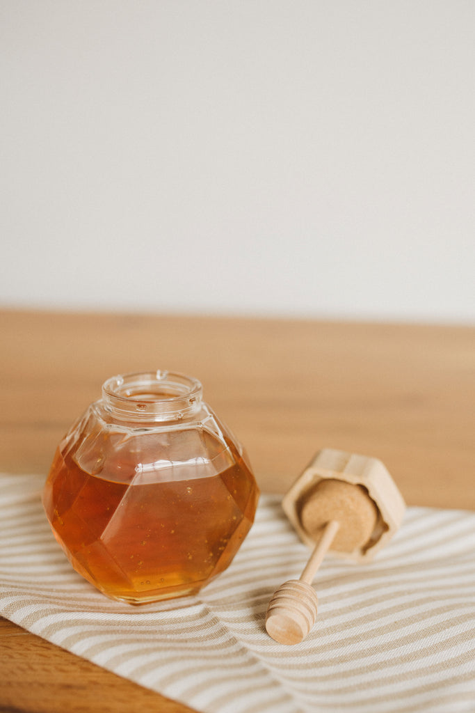 Close-up of Glass Honey Jar with Wooden Dipper for Mess-Free Honey Drizzling.